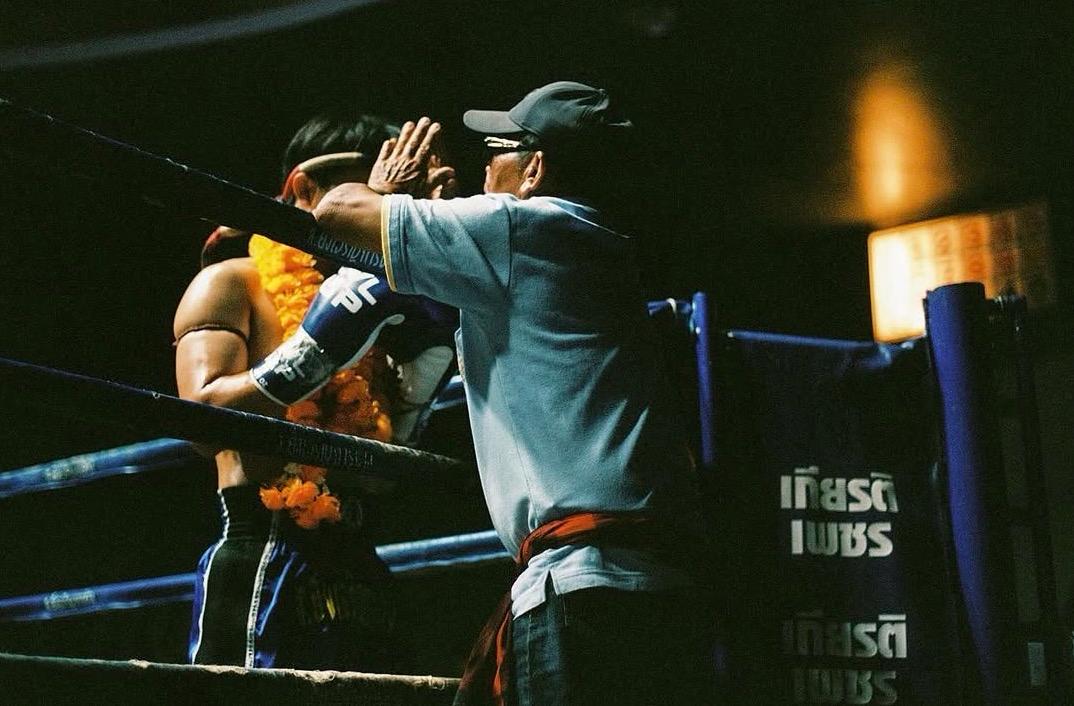 Two Muay Thai fighters kneeling in prayer before a bout